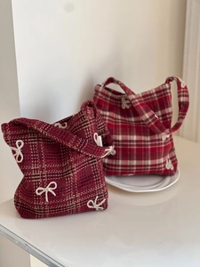Detail of red plaid tweed handbags with white bow accents and textured fabric finish