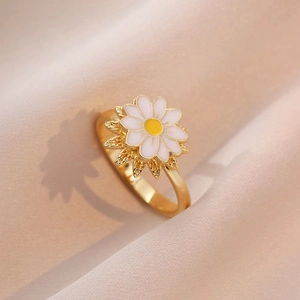 Drehbarer Gänseblümchen-Ring aus vergoldeter Legierung mit Emaille auf rosa Stoffhintergrund