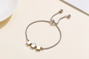 Detail of adjustable silver chain bracelet with white tulip charms and golden beads