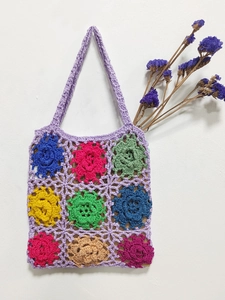 Close-up of handmade crochet tote bag with colorful 3D flower patterns and purple base
