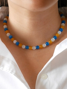 Detail of necklace with glacier blue, orange, and white cat-eye beads on collar