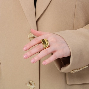 Polished 18K gold plated wavy chunky stainless steel open ring worn by a model