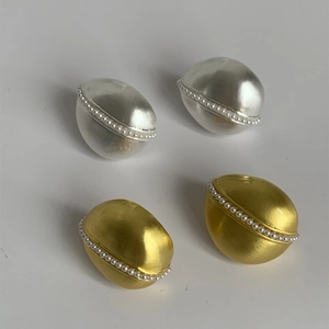 Dettaglio di orecchini ovali opachi in oro e argento con bordo di perle decorative