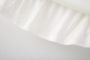 Macro shot of white woven fabric with professional double-needle stitching and smooth hem