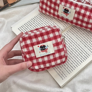 Detail of red gingham knit pouch with lace trim and cat logo on white fabric