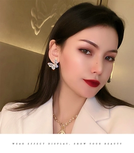 Detailed view of silver butterfly stud earrings with sparkling cubic zirconia on a model