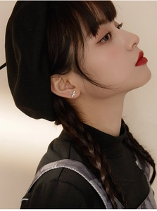 Detail of silver angel wing stud earrings with pearl accent worn on a female model