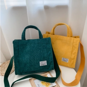 Close-up of corduroy tote bags in dark green and bright yellow with shoulder straps