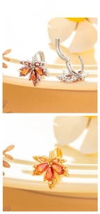 Detailed macro of maple leaf earrings with orange zircons in gold and silver finish