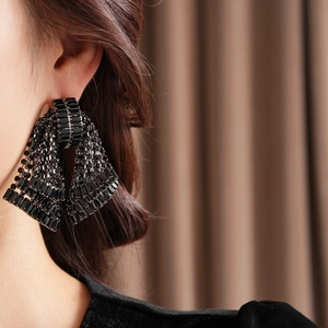 Close-up of a black bow earring with sparkling rhinestones worn on a model's ear