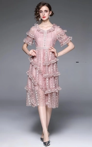 Détail de robe en dentelle rose avec broderie florale et ourlet à volants multicouches