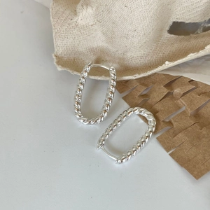 Macro shot of silver twisted rope U-shaped hoop earrings with a textured weave finish