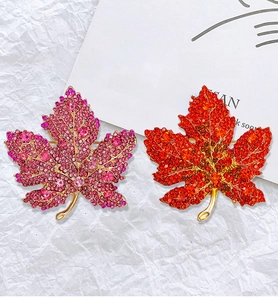 Detailed comparison of sparkling maple leaf brooches with dense and sparse rhinestone settings