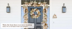 Detail of white pumpkins and golden maple leaves on autumn door wreath and garland