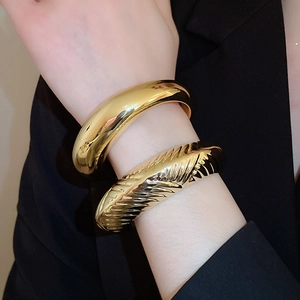 Gros plan sur des bracelets dorés à rayures texturées et surface lisse au poignet