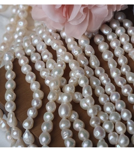 Macro shot of high luster 6.5-7mm baroque freshwater pearls on dark wood with pink flowers