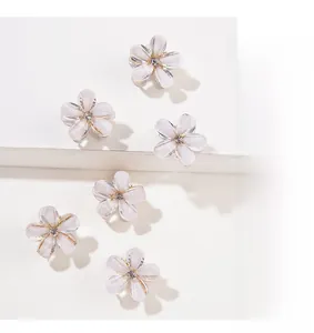 Macro shot of 6 mini flower hair clips with crystals and opalescent petals on white steps