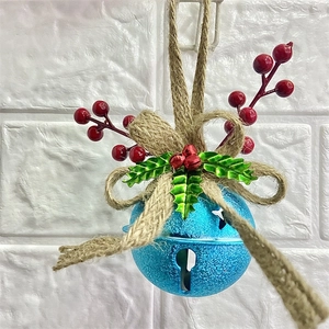 Detail of blue Christmas bell ornament with red berries, holly leaves and burlap bow