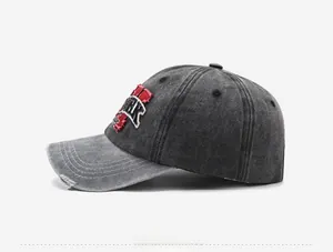 Detail of vintage washed denim baseball cap featuring distressed holes and red embroidery