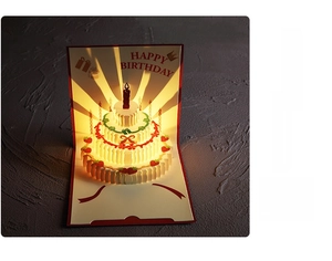 Detail of 3D birthday card featuring a layered cake design with glowing warm lights