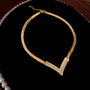 Close-up of a gold-plated V-shaped necklace with micro-pave crystals on black velvet