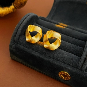 Macro view of gold matte twisted stud earrings in a premium black velvet jewelry box