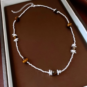 Gros plan d'un collier en perles d'oeil de tigre avec entretoises en argent en boîte