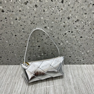 Close-up of silver woven leather bag with geometric texture and golden zipper detail