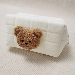 Detailed macro view of plush quilted cosmetic bag with cute brown bear head decoration