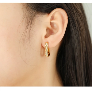 Detail of gold-plated rectangular hoop earring with zircon pavé setting on ear