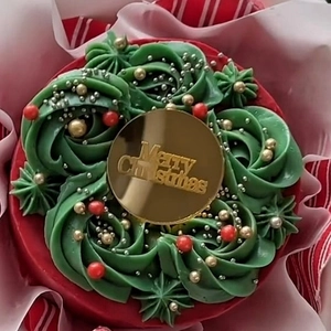 Merry Christmas acrylic cake topper on red festive cake with green wreath icing