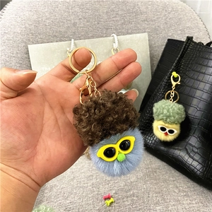 Close-up of blue plush cauliflower keychain with glasses and brown hair detail