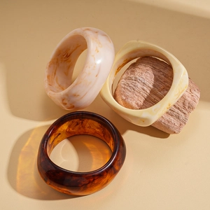 Detail of chunky resin bracelets in amber tortoiseshell and marble patterns with geometric shapes