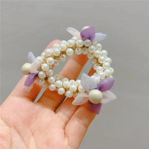 Close-up of a pearl hair tie featuring delicate purple mesh flowers and large pearl beads