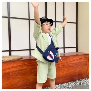 Low angle shot of a boy wearing a dark blue shark print chest bag with canvas texture