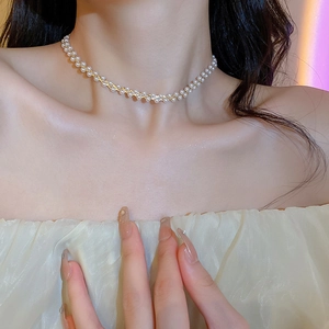 Nahaufnahme der vergoldeten Perlenkette mit weißen Perlen am Hals des Models