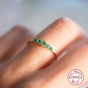 Macro shot of 925 sterling silver ring with five green zircons on a woman's finger