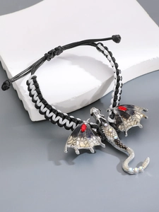 Detail van handgeweven draakarmband met zilveren vleugels en rode edelstenen