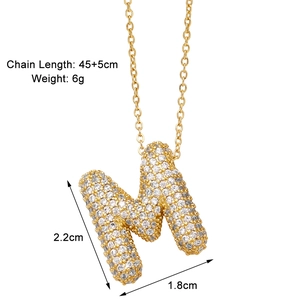 Detail view of gold M initial necklace with zircon stones and product dimensions