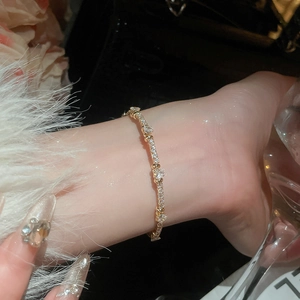 Close-up of golden bangle featuring heart-shaped zircon stones on a female wrist
