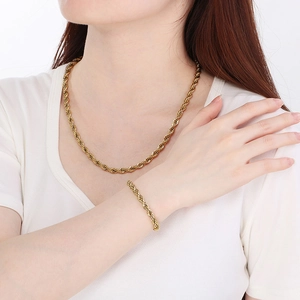 Détail d'un ensemble collier et bracelet en chaîne torsadée dorée porté sur un modèle