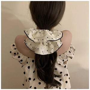 Polka dot satin scrunchie with lace trim shown on model for elegant hairstyle