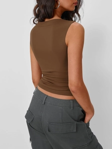 Dettaglio di un top marrone senza maniche aderente con pantaloni cargo grigi