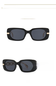 Detail view of square black sunglasses featuring gold hollow chain temples and dark grey lenses