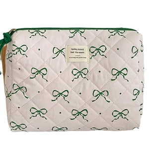 Quilted beige cosmetic bag with green bow print and tassel zipper for travel storage
