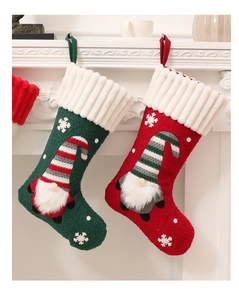 Dettaglio calze di Natale in maglia rosse e verdi con ricamo di gnomi su camino bianco