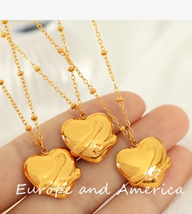 Detail showing the 18K gold hug heart pendant and beaded chain held by hand