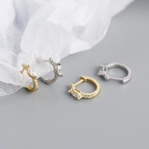Close-up of gold and silver S925 earrings with marquise-cut zircon stones on white paper