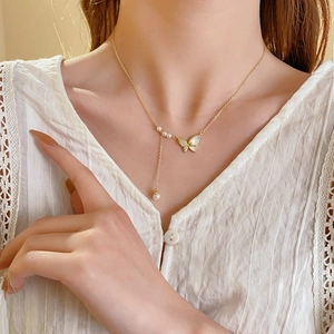 Gros plan d'un collier pendentif papillon doré avec des perles sur un mannequin