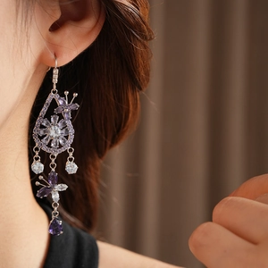 Close-up of elegant zircon butterfly and flower tassel earrings on model ear